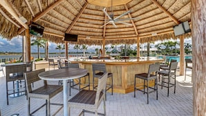 A covered outdoor bar area with a pool view, featuring wicker furniture and a wooden bar counter. - *NAPLES HOUSE WITH POOL near Marco Island (Naples)