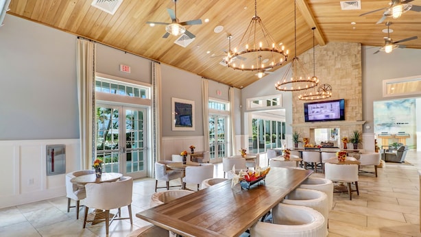 A spacious dining area with a long wooden table, white cushioned chairs, and a chandelier. - *NAPLES HOUSE WITH POOL near Marco Island (Naples)