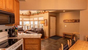 A kitchen with wooden cabinets, a stove, and a dining area with a bench.