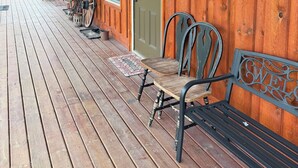 A wooden porch with a bench, a door, and a mounted deer antler. - Kara Creek Ranch - Double Bed Cabin with Kitchen #7 (Sundance)