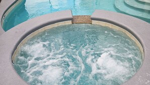 Ein Whirlpool mit gefliestem Rand und einem kleinen Wasserfall in der Mitte.