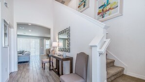 Ein modernes Interieur mit einer Treppe, einem Essbereich mit Tisch und Stühlen sowie einem Wohnzimmer mit Sofa und Lampe.