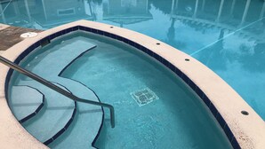 Une piscine avec un bord carrelé et un couvercle de vidange.