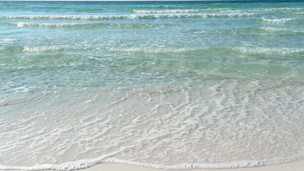 Une plage à l’eau claire et aux vagues douces.