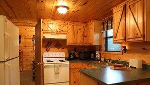 A cabin-style kitchen with wooden cabinets, a stove, microwave, and a sink. - One Bedroom with Loft Sleeps Six By Cedar Creek Golf Course & Broken Bow Lake (Broken Bow)
