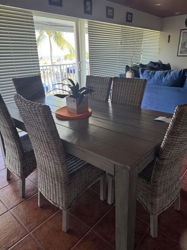 A dining area with a wooden table, wicker chairs, and a potted plant.