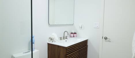 A bathroom with a white sink, wooden vanity, and a mirror.