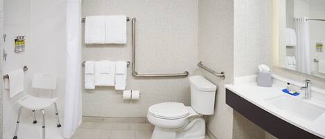 Een moderne badkamer met een wit toilet, een wastafel met donker aanrechtblad en een douchegedeelte.