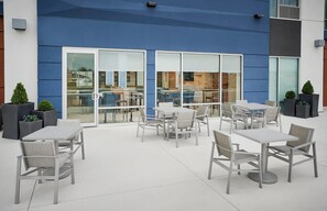 An outdoor patio area with tables and chairs, large windows, and potted plants. - Holiday Inn Express & Suites Windsor East - Lakeshore by IHG (Lakeshore)