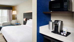 A hotel room with a bed, a desk, a microwave, a coffee maker, and a trash bin. - Holiday Inn Express & Suites Windsor East - Lakeshore by IHG (Lakeshore)