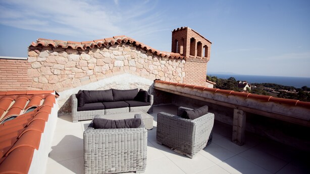 A rooftop terrace with stone walls, a brick chimney, and wicker furniture. - A breathtaking view 5 minutes from the Chateau de Brégancon (La Londe-les-Maures)