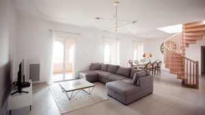 A spacious living room with a large sectional sofa, a dining area, and a wooden staircase. - A breathtaking view 5 minutes from the Chateau de Brégancon (La Londe-les-Maures)