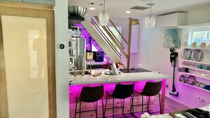A modern kitchen with a central island, bar stools, and a dining area.