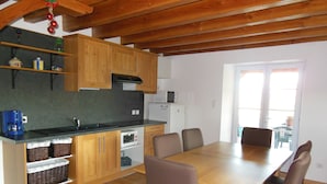 Una cocina compacta con armarios de madera, microondas integrado y un comedor con mesa y sillas de madera.