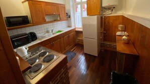 Eine Küche mit Holzschränken, einem Herd, einer Mikrowelle und einem Kühlschrank.