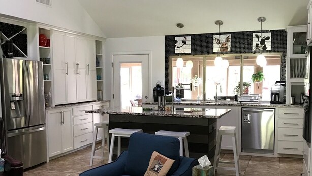 A spacious kitchen with white cabinets, a blue chair, and a tiled floor. - Great Location close to everything (Texarkana)