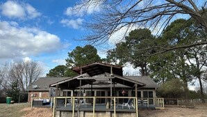 A rustic cabin with a covered porch, a fenced yard, and a satellite dish. - Great Location close to everything (Texarkana)