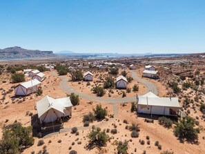 A desert landscape with multiple white tents arranged in rows, connected by winding paths.