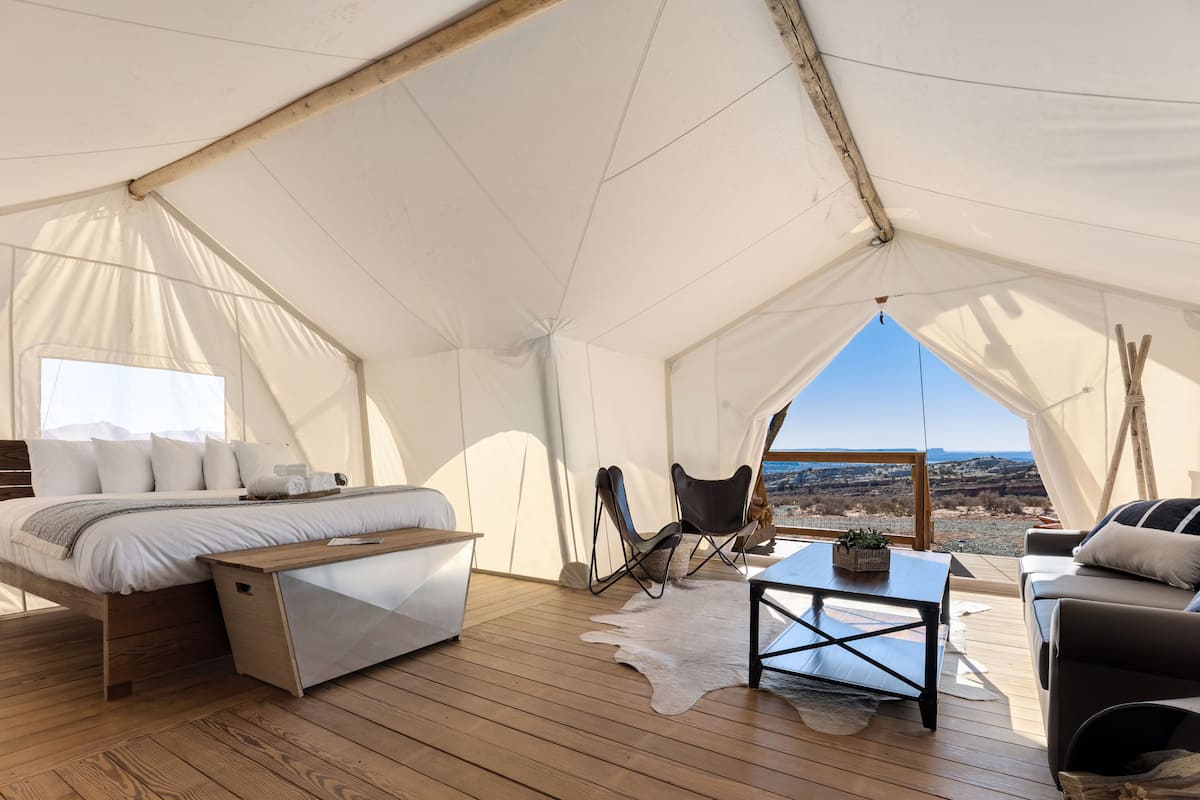 Een tentaccomodatie met een bed, zithoek en uitzicht op het landschap.