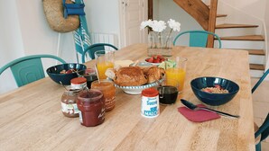 Una mesa de desayuno con croissants, fruta y bebidas.
