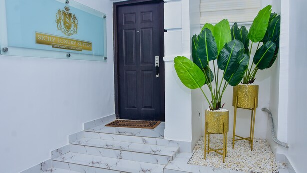 Una escalera que lleva a una puerta con un cartel que indica "Sicily Luxury Suites".