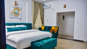 Un dormitorio moderno con una cama color aguamarina, ropa de cama blanca y un reposapiés a juego.