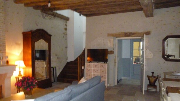 A living room with a blue sofa, a wooden staircase, a TV, and a mirror on the wall. - Gîte en Sancerrois (Menetou-Râtel)