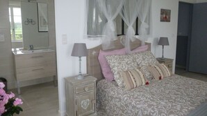 A bedroom with a bed, bedside tables, a nightstand, a mirror, and a window with sheer curtains. - Gîte en Sancerrois (Menetou-Râtel)