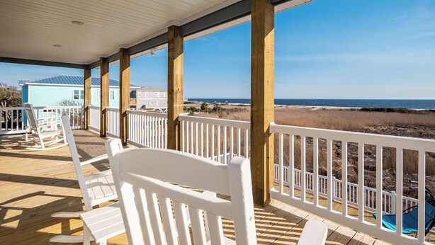 A wooden deck with white railings and a view of the beach and ocean. - Ocean Wind: Kid-friendly and Dog-friendly Ocean View Home with Private Pool (Oak Island)