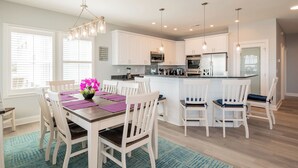 A modern kitchen with white cabinets, a central island, and pendant lighting. - Ocean Wind: Kid-friendly and Dog-friendly Ocean View Home with Private Pool (Oak Island)