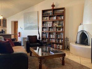 Un salon chaleureux avec un canapé en cuir, une table basse en verre, une bibliothèque en bois et une cheminée.