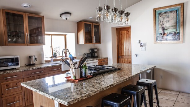 Una cocina moderna con encimeras de granito, armarios de madera y una isla grande con taburetes de bar.