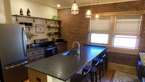Uma cozinha moderna com uma ilha central, banquetas, frigorífico e micro-ondas.
