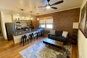 A modern kitchen with a central island, bar stools, and a dining table. - Main Street Retreats 104 Cozy, New Downtown Apt. 104 (Waynesville)