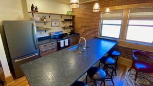 Cozinha moderna com uma ilha grande, banquetas e uma geladeira.