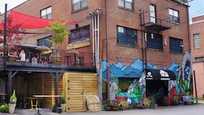 A two-story building with a rooftop patio area, a mural on the side, and a wooden door. - Main Street Retreats 105 - Brand New Apt. 105 (Waynesville)