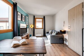 A modern living room with a wooden dining table, a sofa, a TV, and a lamp.