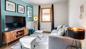 A modern living room with a TV, sofa, and lamp.