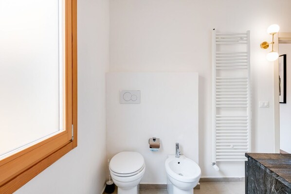 Un baño moderno con inodoro, bidé y un perchero para toallas.