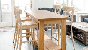 Een eetgedeelte met een houten tafel en stoelen, een blauwe bank en een rieten mand.