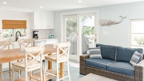 Een moderne keuken met witte kastjes, een eettafel met stoelen, een blauwe bank en een decoratieve walvissculptuur.