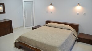A bedroom with a bed, bedside tables, a wardrobe, and wall-mounted lights. - Descobrir Madeira com Carro Grátis (Estrada Padre Alfredo Vieira Freitas)