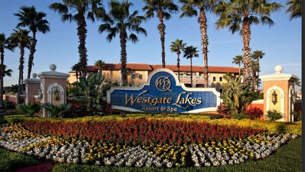 Een bord voor Westgate Lakes Resort & Spa, omringd door palmbomen en een bloembed.