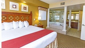 Een hotelkamer met een groot bed, een badkamer met een bad en uitzicht op het interieur van het hotel.