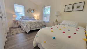 Un dormitorio con dos camas, un escritorio y una ventana.