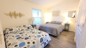 Een slaapkamer met twee bedden, een raam met zonwering, nachtlampjes en een wanddecoratie.