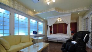 Une chambre à coucher avec un lit à baldaquin, un fauteuil de massage, un canapé et une petite table.
