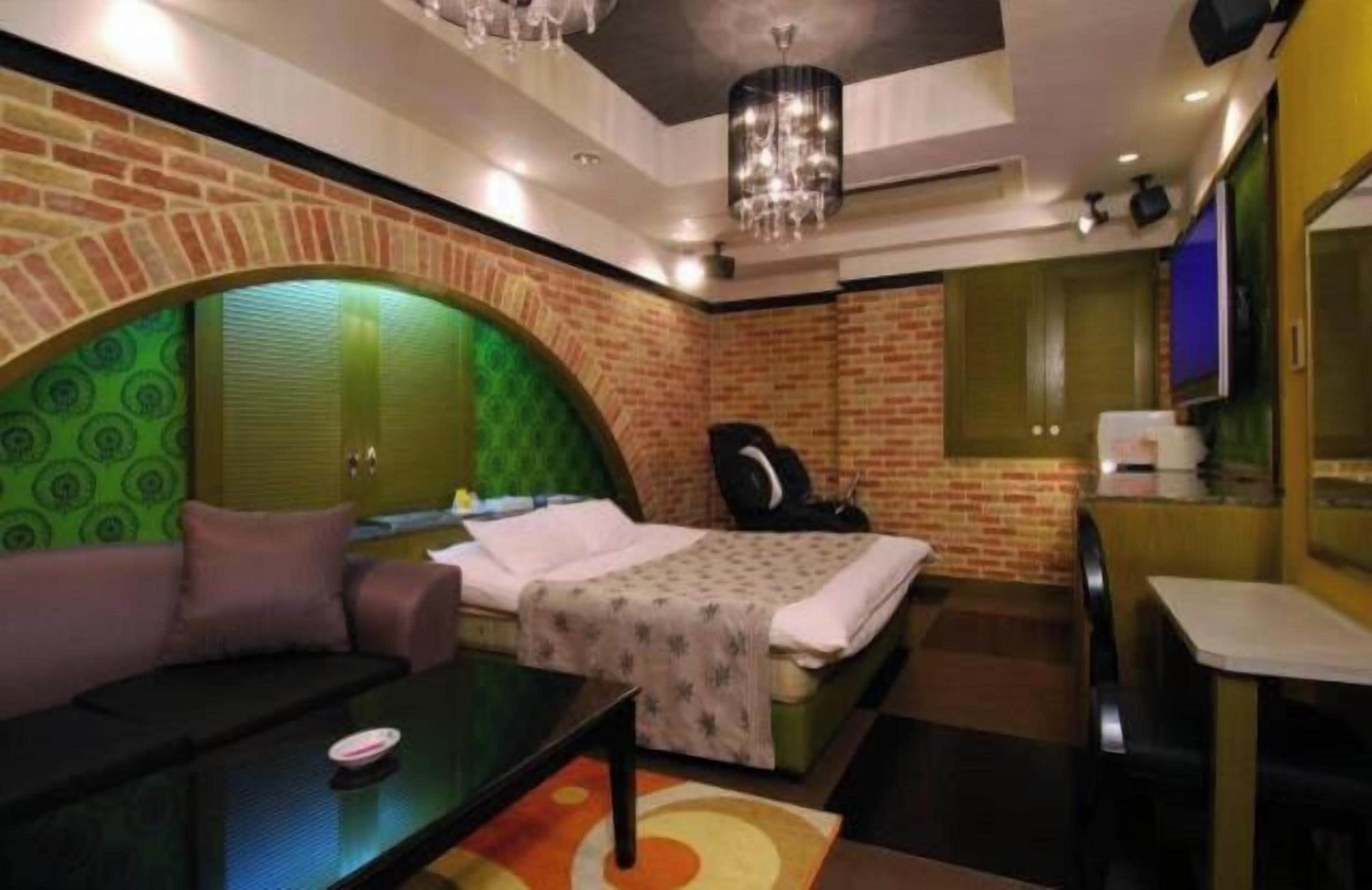 Una habitación con cama, sofá, escritorio y sillón de masaje.