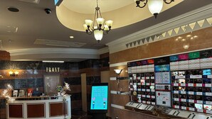 Ein Hotel-Empfangsbereich mit digitalem Display, einer Rezeption und einer Wand mit Zimmerauswahl.