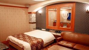 Una habitación de hotel con cama, un mueble de madera con espejo, un sofá de cuero y una pequeña mesa.
